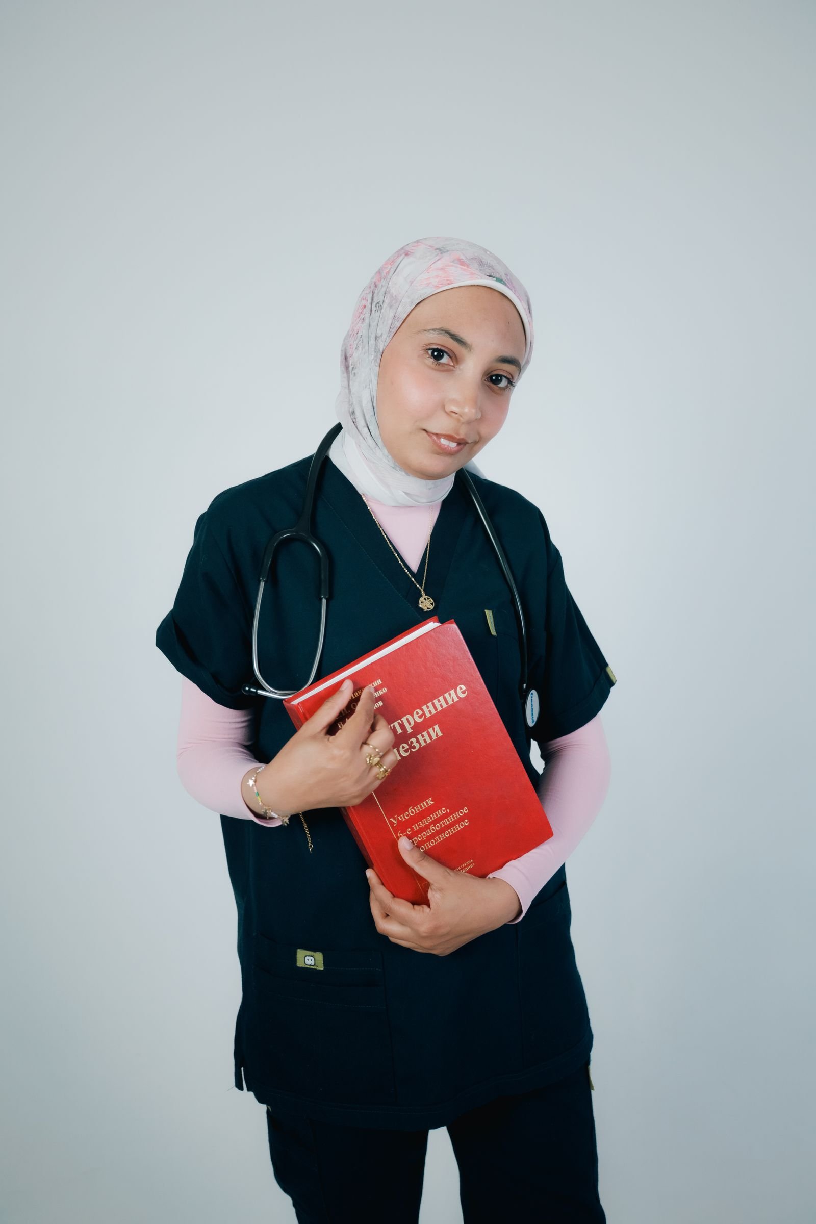 ممرضة بالحجاب تحمل كتابًا طبيًا